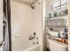 Bathroom with white tile walls, a tub with a shower, and a storage rack near the toilet at 12125 Helena St, Brighton, CO 80603