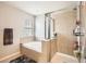 Bright bathroom featuring a shower and a soaking tub under a window with blind for natural light at 12125 Helena St, Brighton, CO 80603