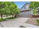 Charming two-story home with gray siding, stone accents, mature trees, and a two car garage at 12125 Helena St, Brighton, CO 80603