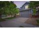 Charming two-story home with gray siding, stone accents, mature trees, and a two car garage at 12125 Helena St, Brighton, CO 80603