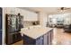 Bright kitchen with white cabinets, stainless steel appliances, and a blue island near the living room at 12125 Helena St, Brighton, CO 80603