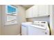 Bright laundry room featuring white washer and dryer, cabinets and natural light from the window at 9255 Melborne Ct, Parker, CO 80134