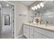Bathroom with double sinks, white cabinets, large mirror, and views of the shower and hallway at 5255 Ridge Trl, Littleton, CO 80123