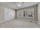 An empty bedroom with light gray walls, carpet, three windows, white trim, and a ceiling fan at 5255 Ridge Trl, Littleton, CO 80123