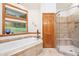 Bathroom features a corner tub and glass enclosed shower with a view of the outdoors at 2164 Foothills S Dr, Golden, CO 80401
