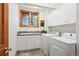 Well-lit laundry room with modern washer and dryer, sink, and ample cabinet space at 2164 Foothills S Dr, Golden, CO 80401