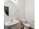 A half bathroom featuring a pedestal sink, round mirror, and new fixtures at 5021 S Rome St, Aurora, CO 80015