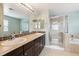 Bathroom featuring double sinks, dark cabinets, and walk-in shower with glass door at 5021 S Rome St, Aurora, CO 80015