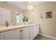 Bathroom with a double sink vanity, stylish white cabinetry, and elegant fixtures offers a luxurious feel at 5128 Longs Peak St, Brighton, CO 80601