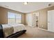 Bright bedroom featuring large window and neutral carpet flooring and ensuite bathroom at 5128 Longs Peak St, Brighton, CO 80601