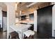 A stylish kitchen with white quartz island, brick backsplash, dark cabinetry, and stainless steel appliances at 1301 Wazee St # 3C, Denver, CO 80204