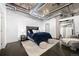 Comfortable main bedroom featuring a gray headboard, lots of pillows, soft rug, and exposed ductwork at 1301 Wazee St # 3C, Denver, CO 80204