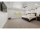 Primary bedroom featuring tray ceiling, ceiling fan, neutral carpet, and large windows at 6405 Eagle Feather Trl, Littleton, CO 80125