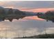 Scenic pond reflecting a colorful sunset and surrounding trees and mountains in the background at 6405 Eagle Feather Trl, Littleton, CO 80125