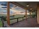 Relaxing porch with wooden pillars overlooking expansive land with flowers, lawn, and a tennis court at 11881 County Road 37, Fort Lupton, CO 80621