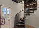 A unique dark wood spiral staircase connecting floors with views to the outside from the lower level at 11881 County Road 37, Fort Lupton, CO 80621