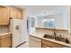 Well-lit kitchen with double sink, neutral countertops, and a view into the dining area at 371 Granby Way # C, Aurora, CO 80011