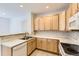 Bright kitchen with light wood cabinets, stainless steel sink, and a view into another room at 371 Granby Way # C, Aurora, CO 80011