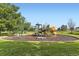 Community playground with slides, swings, and climbing structures on a mulch base, surrounded by grass and trees at 371 Granby Way # C, Aurora, CO 80011