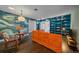 Living room featuring a large orange sectional, a blue accent wall, and custom built-in shelves at 6630 E Virginia Ave, Denver, CO 80224