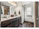 Modern bathroom with double sinks, dark wood vanity, and plank flooring at 11861 Fairplay St, Commerce City, CO 80603
