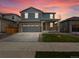 Charming two-story home with stone accents, a two-car garage, a well-maintained lawn and colorful sunset at 546 Red Rock Pl, Brighton, CO 80601