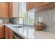 Kitchen counter featuring gray backsplash, faucet, built-in oven and wooden cabinets at 8711 E Hampden Ave # 23, Denver, CO 80231
