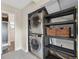 Efficient laundry area featuring stacked washer and dryer plus shelving for storage and a glimpse of the finished bathroom at 9306 Garrison Dr, Broomfield, CO 80021