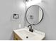 Updated bathroom features a round mirror, a modern sink, and unique towel racks at 12933 E Louisiana Ave, Aurora, CO 80012
