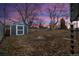 Fenced backyard with a storage shed and mature trees at dusk at 3565 S Holly St, Denver, CO 80237