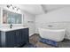 Modern bathroom featuring a deep soaking tub, vessel sink with a dark blue vanity at 10288 Olathe Way, Commerce City, CO 80022