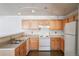 Well-lit kitchen featuring wooden cabinets, white appliances, and modern track lighting at 12158 W Dorado Pl # 204, Littleton, CO 80127