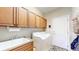 Functional laundry room with upper cabinets, sink, and white washing machine, next to the back door at 1738 Edgewater Pl, Longmont, CO 80504