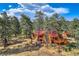 Stunning log home with red roof surrounded by mature trees and a lush yard at 23231 Maricopa Rd, Indian Hills, CO 80454