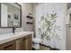 Bathroom with a wood vanity, framed mirror, and a tub with a plant-themed shower curtain at 10595 Boston St, Commerce City, CO 80640