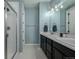 Bright bathroom features a double vanity with black cabinets, white countertops, and a glass-enclosed shower at 10595 Boston St, Commerce City, CO 80640