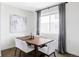 A dining room with a wooden table, six chairs, artwork, and a large window with grey curtains at 2862 S Galapago Ct, Englewood, CO 80110