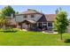 Wide view of the expansive backyard including a covered patio with outdoor seating and mature trees at 11513 Greenbriar Ln, Parker, CO 80138