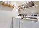 Functional laundry room with white washer and dryer, upper cabinets, and shelving for storage, enhancing home convenience at 11513 Greenbriar Ln, Parker, CO 80138