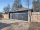 View of a two car garage with black doors, gray brick, and a concrete driveway at 2824 Cherry St, Denver, CO 80207