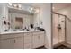 Bright bathroom with double sinks, white cabinets, and a glass-enclosed shower at 21538 E 59Th Pl, Aurora, CO 80019