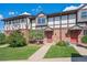 Charming townhome featuring brick facade, Tudor-style accents, manicured lawn, and inviting red front door at 3855 S Monaco St # 182, Denver, CO 80237