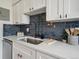 Contemporary kitchen featuring white quartz countertops, undermount sink, designer faucet, and stylish backsplash at 3855 S Monaco St # 182, Denver, CO 80237