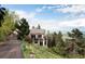 View of the home sitting atop a hill with mature landscaping and trees at 1426 Rembrandt Rd, Boulder, CO 80302