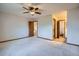 Bright bedroom features a ceiling fan, neutral carpet, and doorways to the bathroom and hallway at 12036 Monaco Dr, Brighton, CO 80602