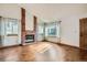 Bright living room featuring hardwood floors, a brick fireplace, and large windows for natural light at 12036 Monaco Dr, Brighton, CO 80602