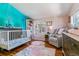 Charming Bedroom featuring a crib, comfortable chair, and soft pink and blue color scheme at 1325 S Ivy Way, Denver, CO 80224