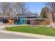 Charming home with a blue door, solar panels, a well-manicured lawn, and mature trees at 1325 S Ivy Way, Denver, CO 80224