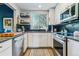 Bright kitchen featuring white cabinets, stainless steel appliances, and black hexagon tile backsplash at 1325 S Ivy Way, Denver, CO 80224