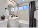 Clean bathroom with white vanity, bathtub, and gray tile at 1040 Hoover Ave, Fort Lupton, CO 80621